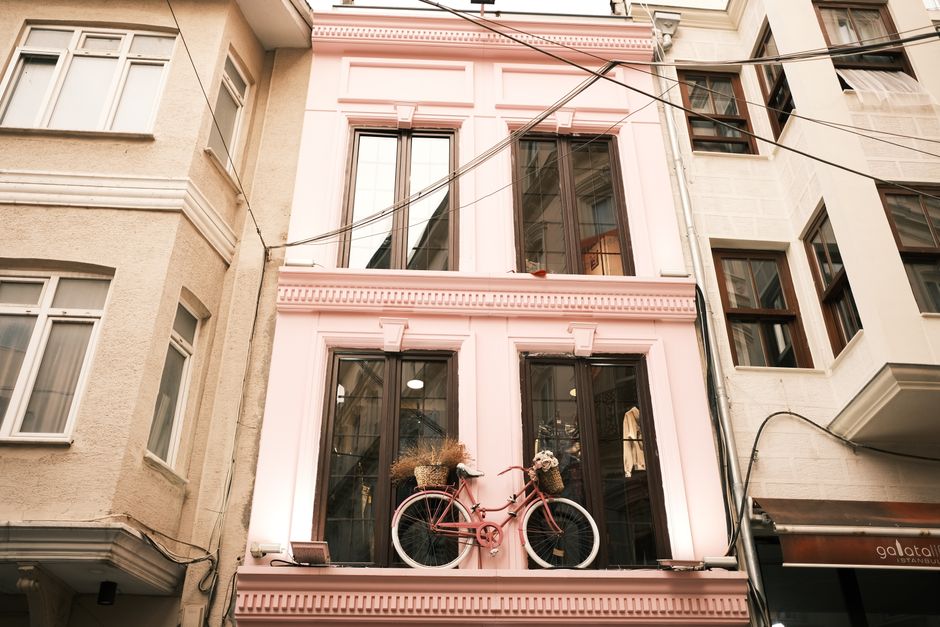 Low-angle shot of a pink building facade featuring a decorative bicycle. Urban charm and creativity.