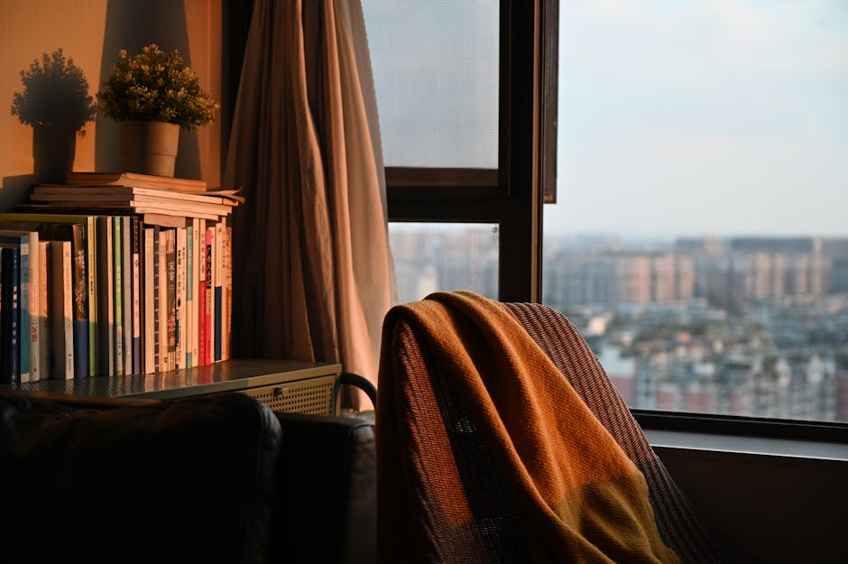 Warm and inviting indoor corner with books and sunset view, perfect for relaxing.
