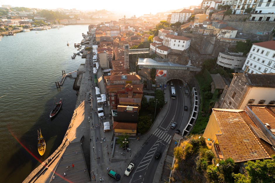 Scenic aerial view of Porto, Portugal, featuring the Douro River, traditional buildings, and roads at sunset.