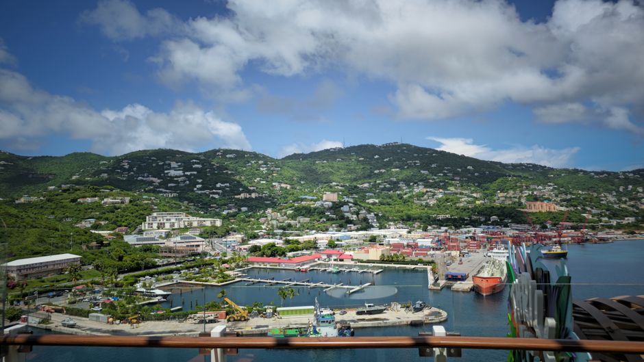 Aerial view of Charlotte Amalie Harbor in St. Thomas with vibrant buildings and lush green hills.