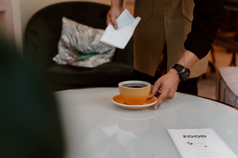 A barista serves coffee in a stylish café, highlighting café culture and hospitality.