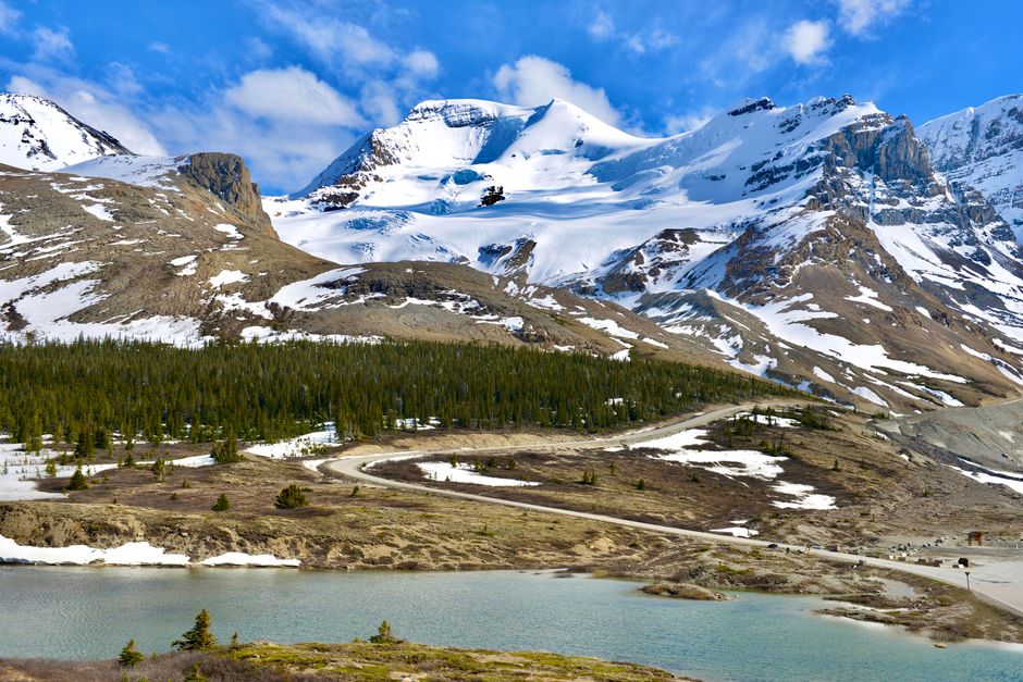 Breathtaking view of the Rocky Mountains with snow and greenery in springtime.