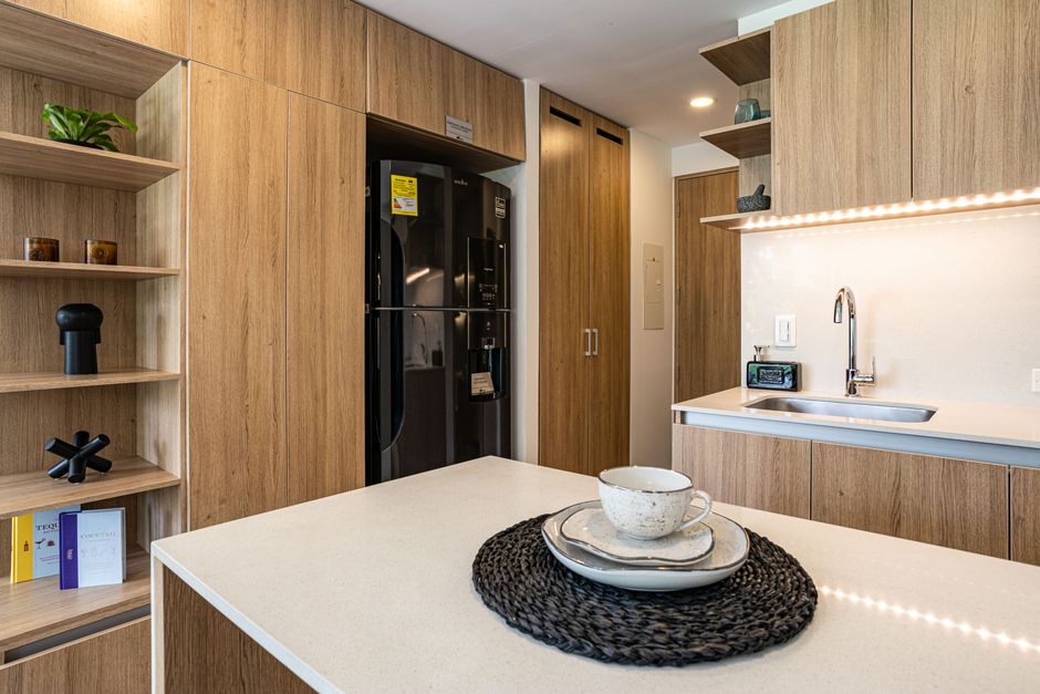 Stylish kitchen interior featuring wooden cabinetry and elegant tableware on a counter in Chía, Colombia.
