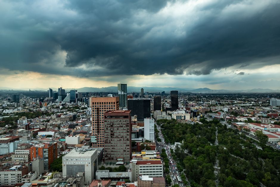 Aerial view of Mexico City's skyline under dark storm clouds, showcasing urban architecture and dramatic weather.