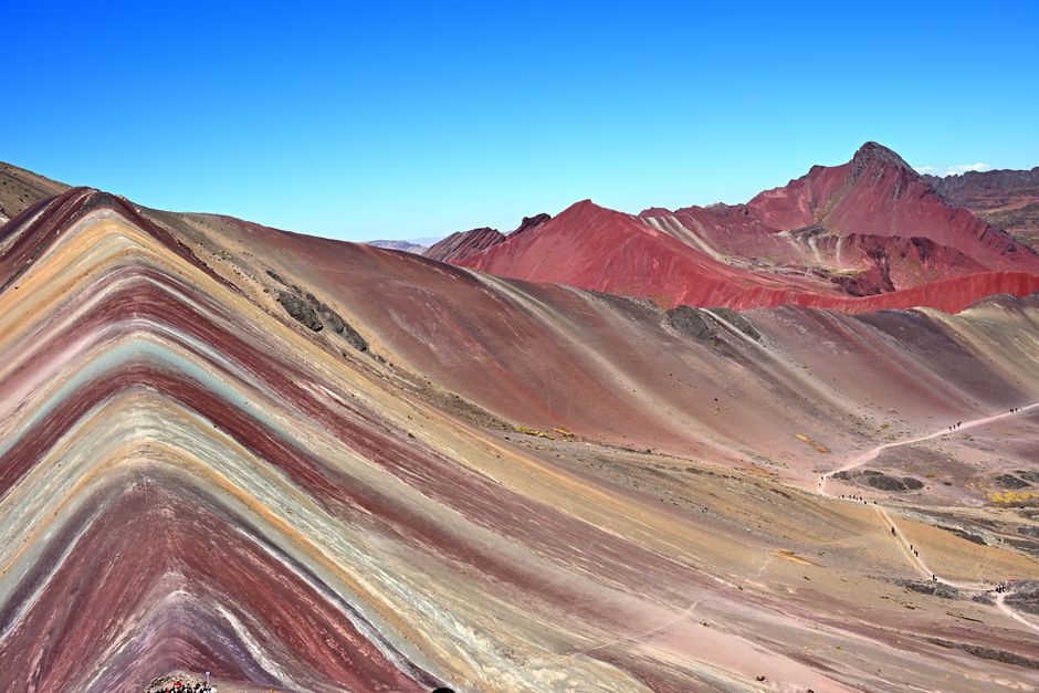 Stunning view of Vinicunca's vibrant rainbow layers under a clear blue sky.