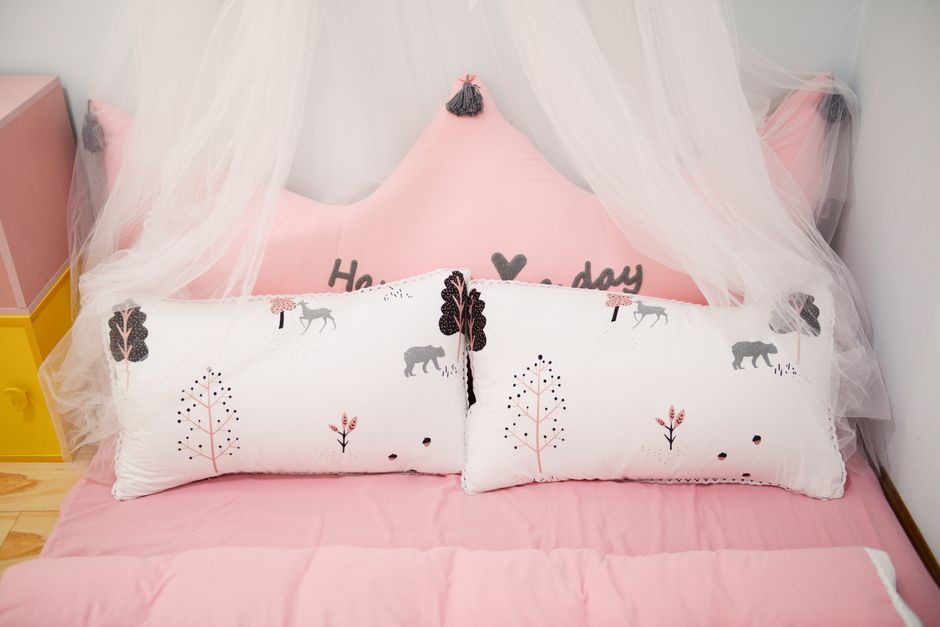 A charming children’s bed featuring pink decor, pillows with animal designs, and a canopy.