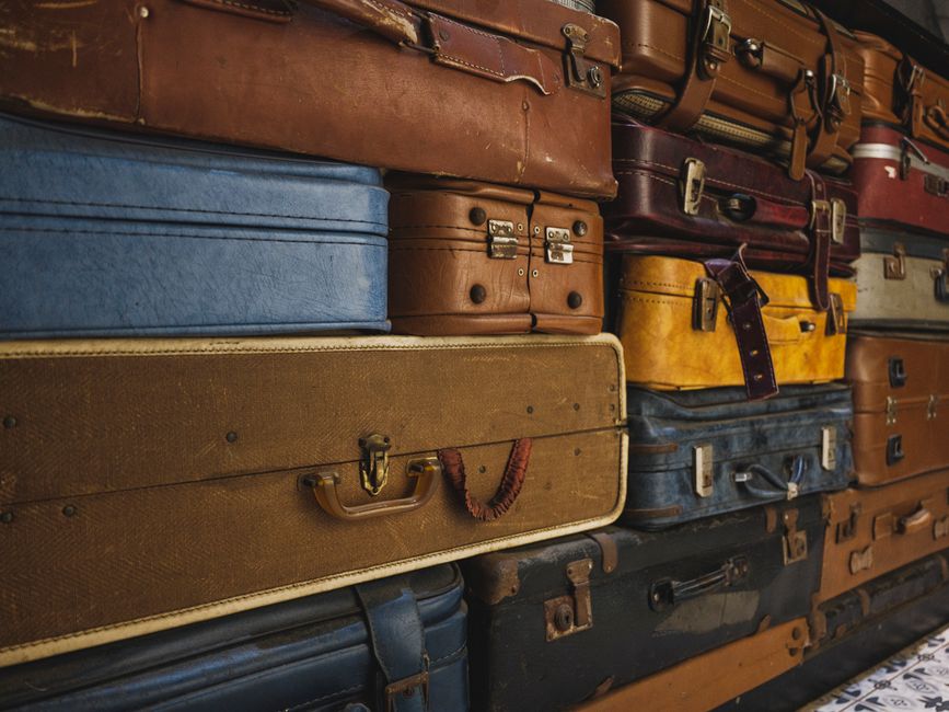 A collection of colorful, worn vintage suitcases stacked together, ideal for decor or travel themes.
