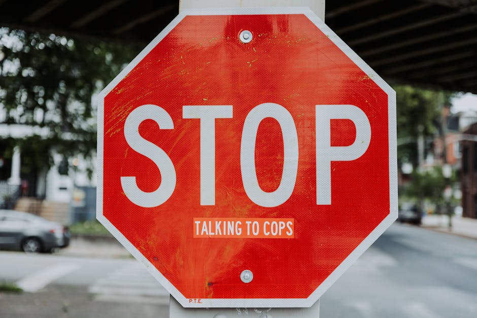 Stop sign with altered message in urban street setting, highlighting social commentary.