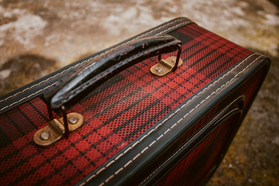 Close-up of a vintage red plaid suitcase with worn handle in Mérida, Venezuela.